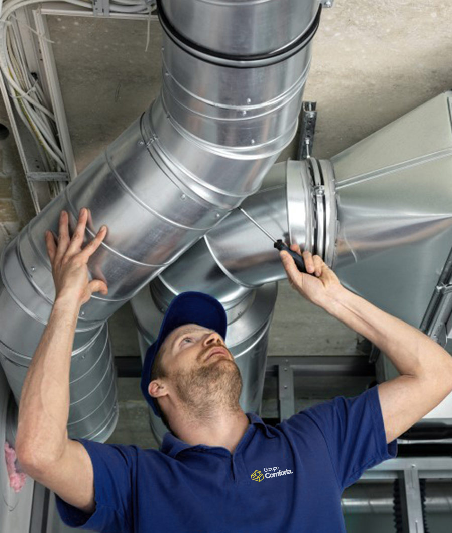Technicien du Groupe Conforta effectuant un entretien professionnel des conduits de ventilation dans un bâtiment.