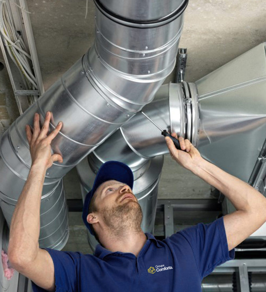 Technicien du Groupe Conforta effectuant un entretien professionnel des conduits de ventilation dans un bâtiment.