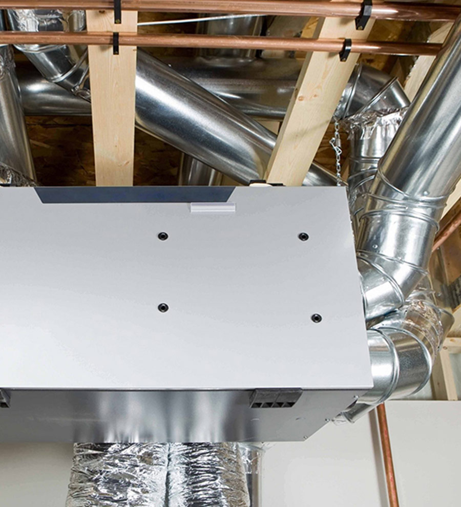 Vue d'un échangeur d'air moderne installé dans un plafond, avec des conduits de ventilation en acier galvanisé et une structure en bois, illustrant un système de ventilation résidentiel ou commercial.